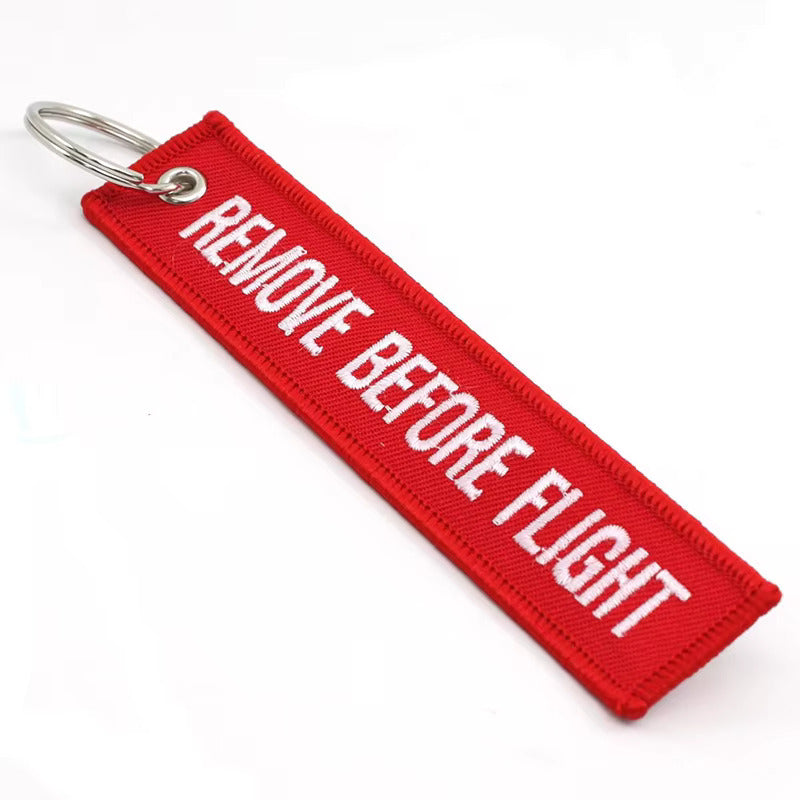 Red 'Remove Before Flight' keychain on a white background