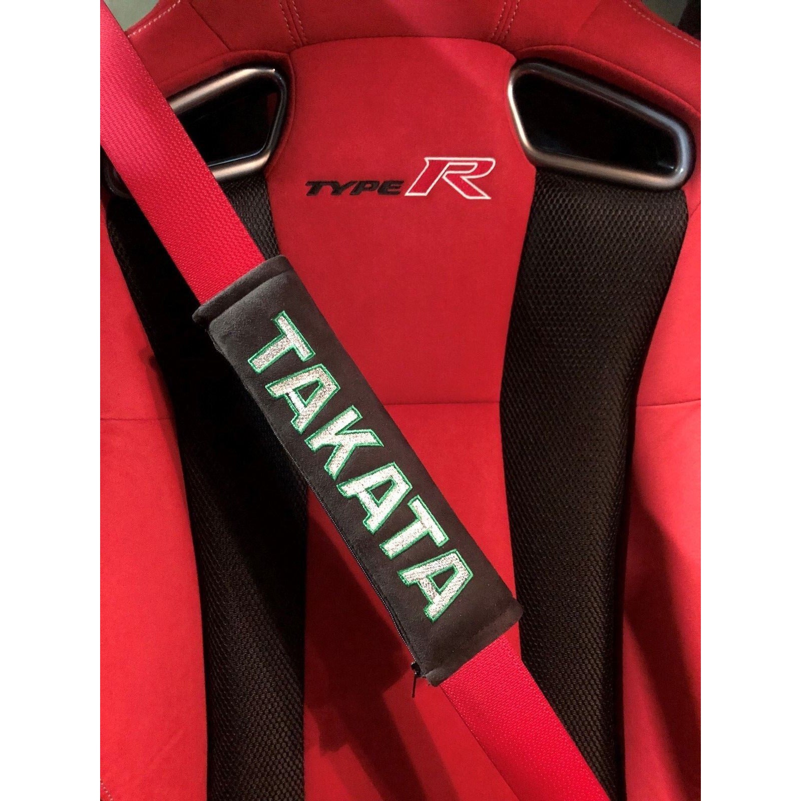 Takata comfort seat belt shoulder pads in black attached to seat belt in a car.