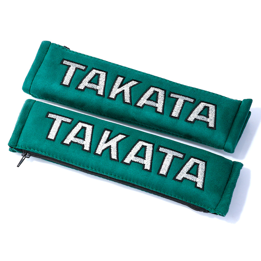 A pair of takata comfort seat belt shoulder pads in green.