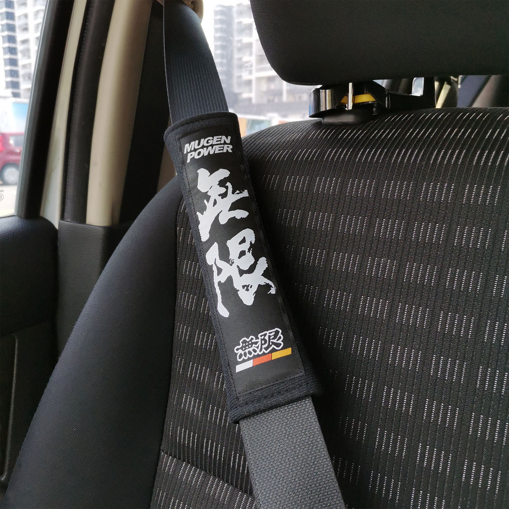 Mugen power seat belt shoulder pads in black installed in car.