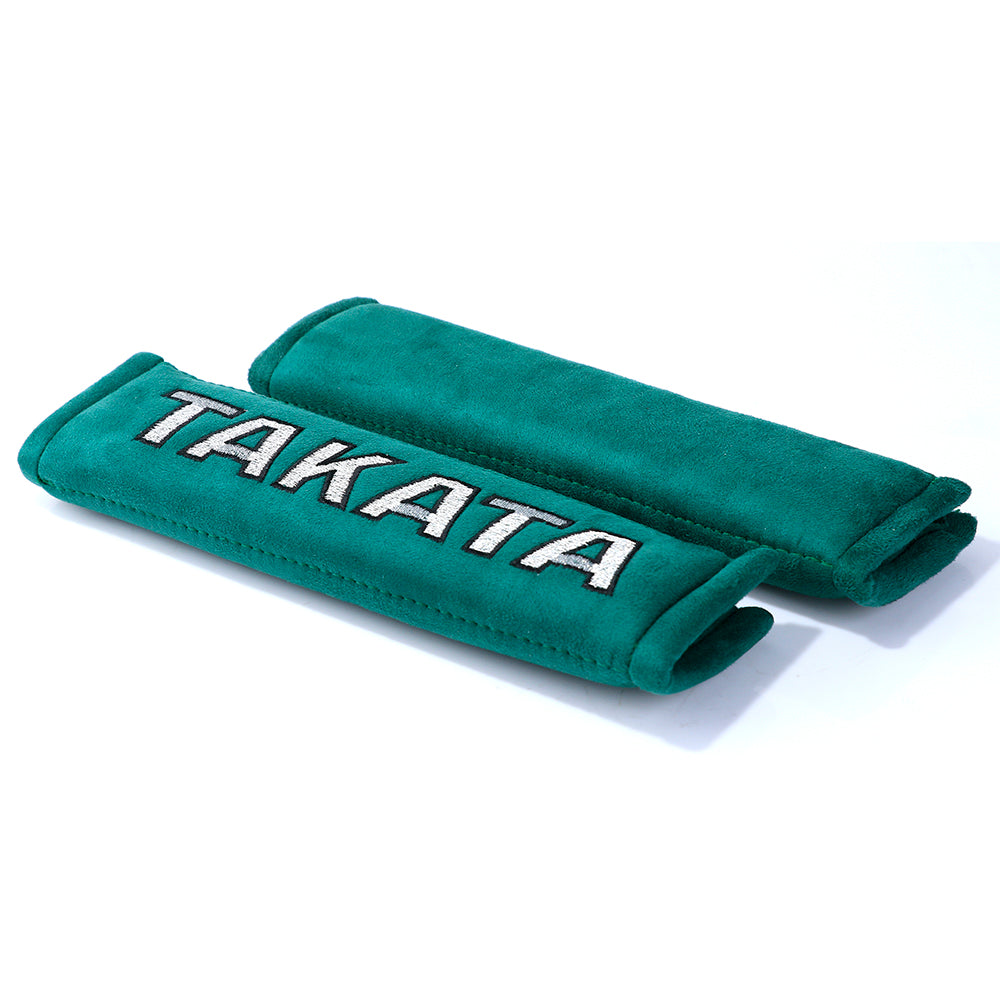 A pair of takata comfort seat belt shoulder pads in green.