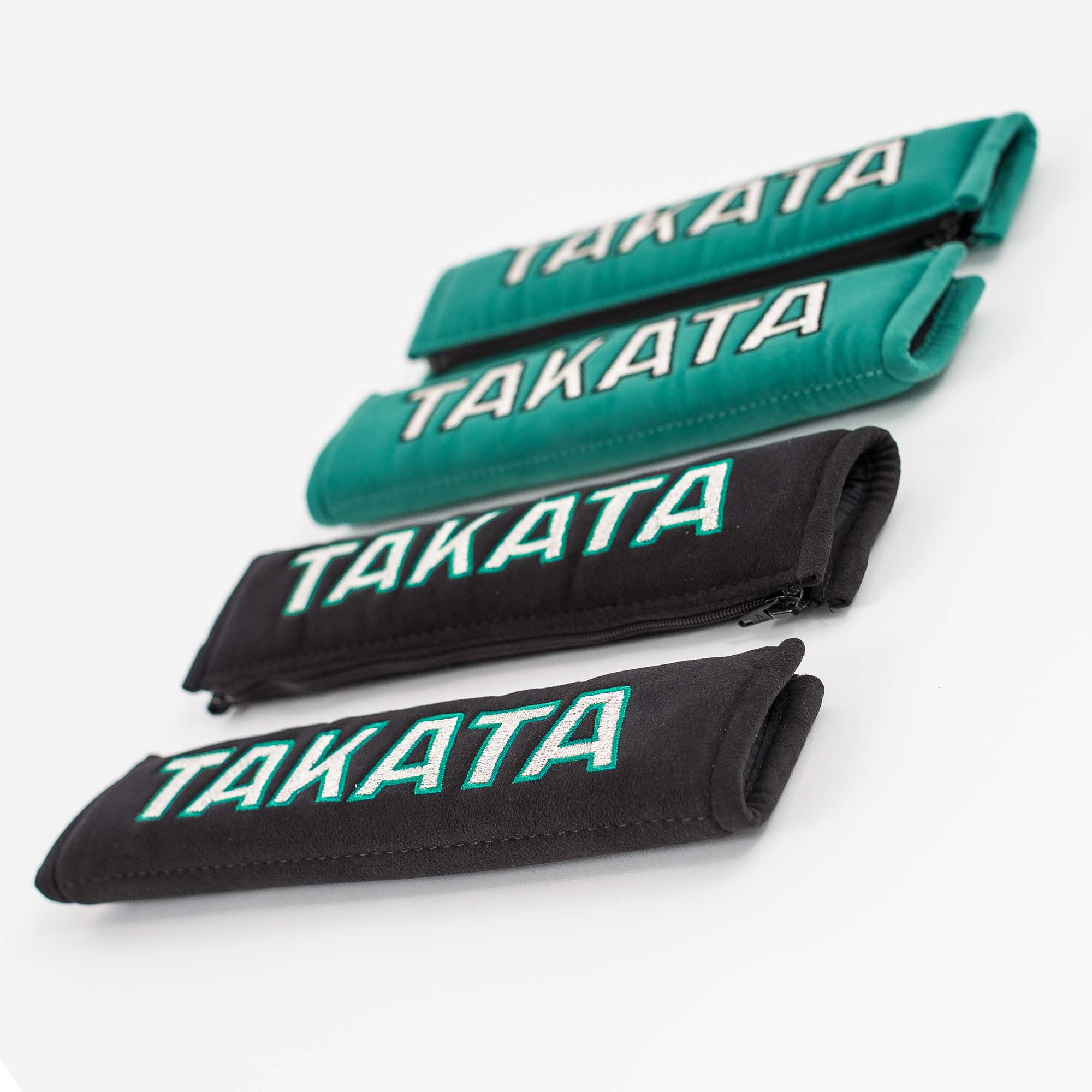 A pair of Takata comfort seat belt shoulder pads in black and green.